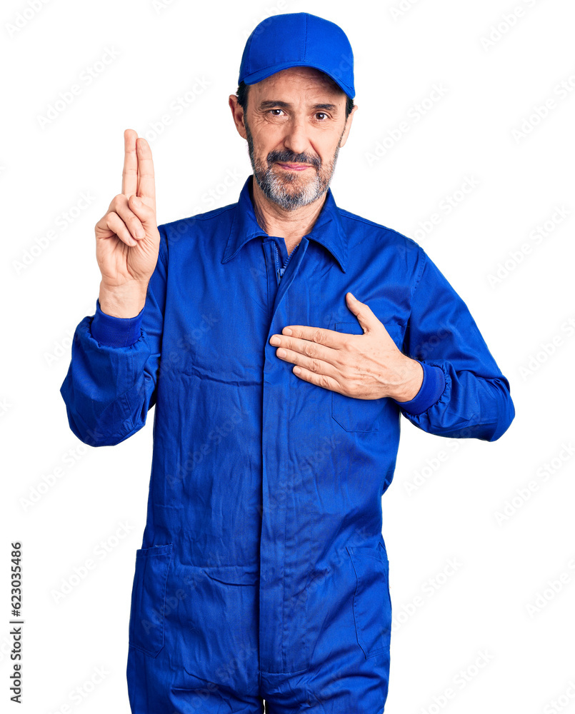 Middle age handsome man wearing mechanic uniform smiling swearing with hand on chest and fingers up, making a loyalty promise oath Middle age handsome man wearing mechanic uniform smiling swearing with hand on chest and fingers up, making a loyalty promise oath