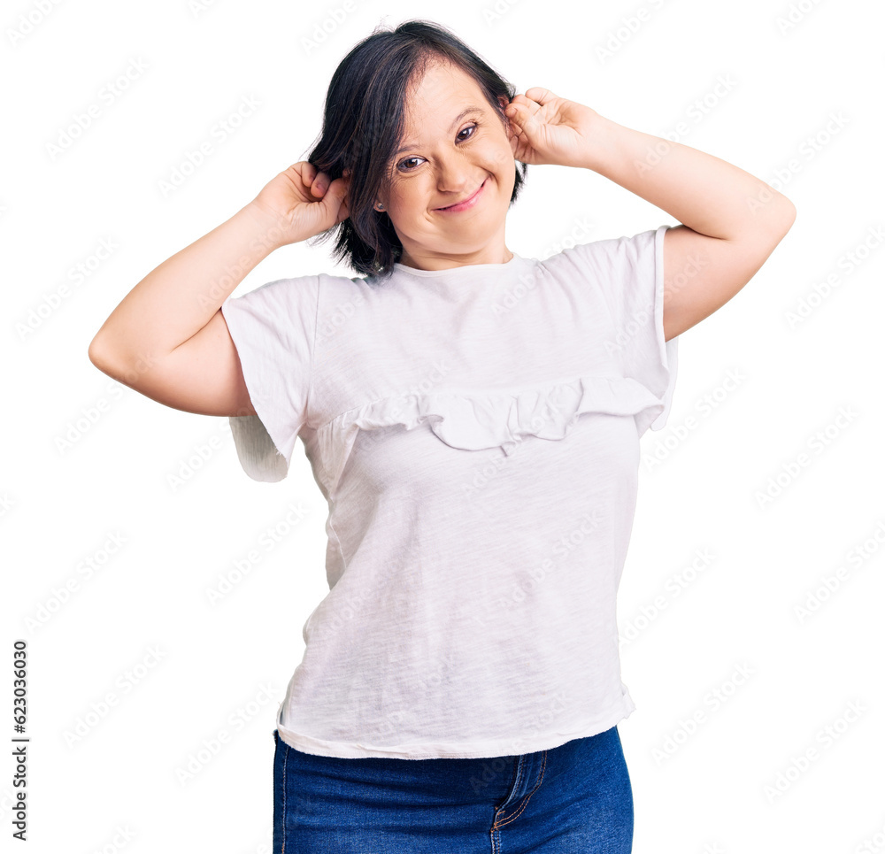 Brunette woman with down syndrome wearing casual white tshirt smiling pulling ears with fingers, funny gesture. audition problem Brunette woman with down syndrome wearing casual white tshirt smiling pulling ears with fingers, funny gesture. audition problem