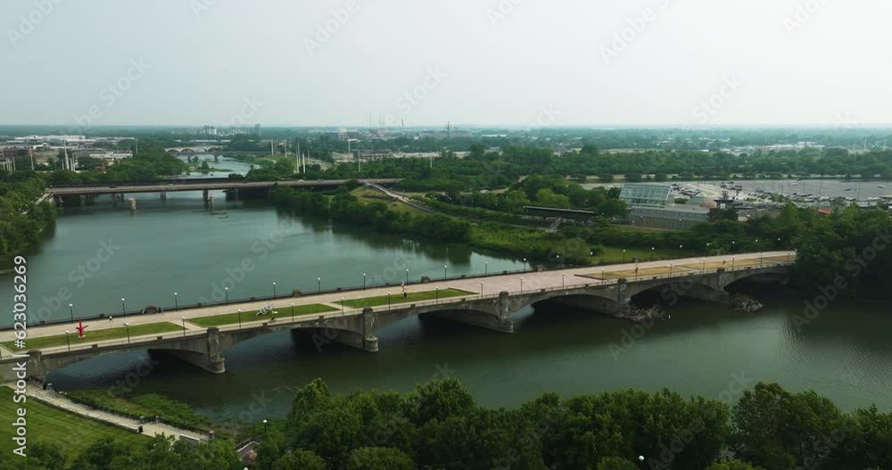 Tranquil Scenic Of Pedestrian Bridge Stands Over The White River At Indianapolis In Indiana, United States. aerial, pan shot Tranquil Scenic Of Pedestrian Bridge Stands Over The White River At Indianapolis In Indiana, United States. aerial, pan shot
