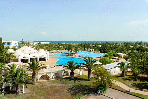 Top view of the hotel complex on the first coastal line of the sea. Beautiful green area with pool and places for relaxation. The concept of tourism, vacations, and recreation