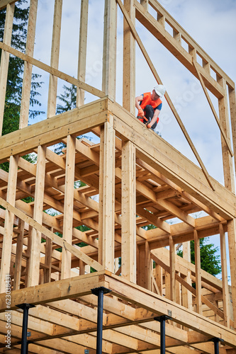 Valokuva Wooden two-story frame house being built by carpenter