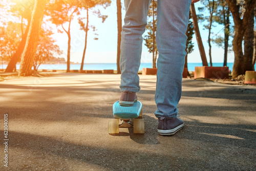 Boy riding skateboard outdoors in summer day in the road, coastline, Child learns to ride a penny board, Travel, sports concept.
