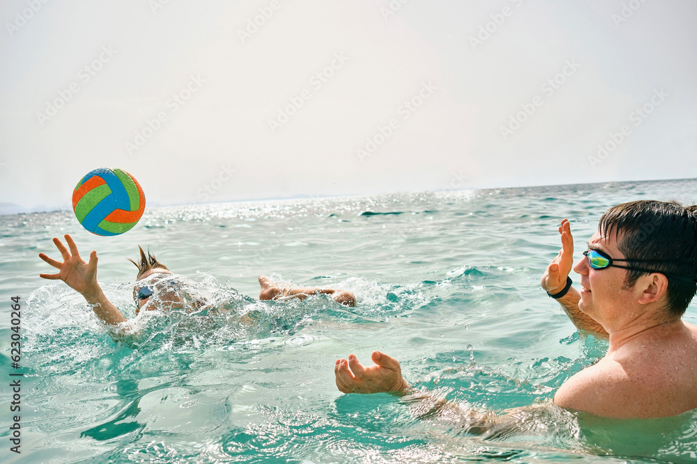 Happy family, father and son bonding, play ball, swim in the sea looking at view enjoying summer vacation. Togetherness Friendly concept