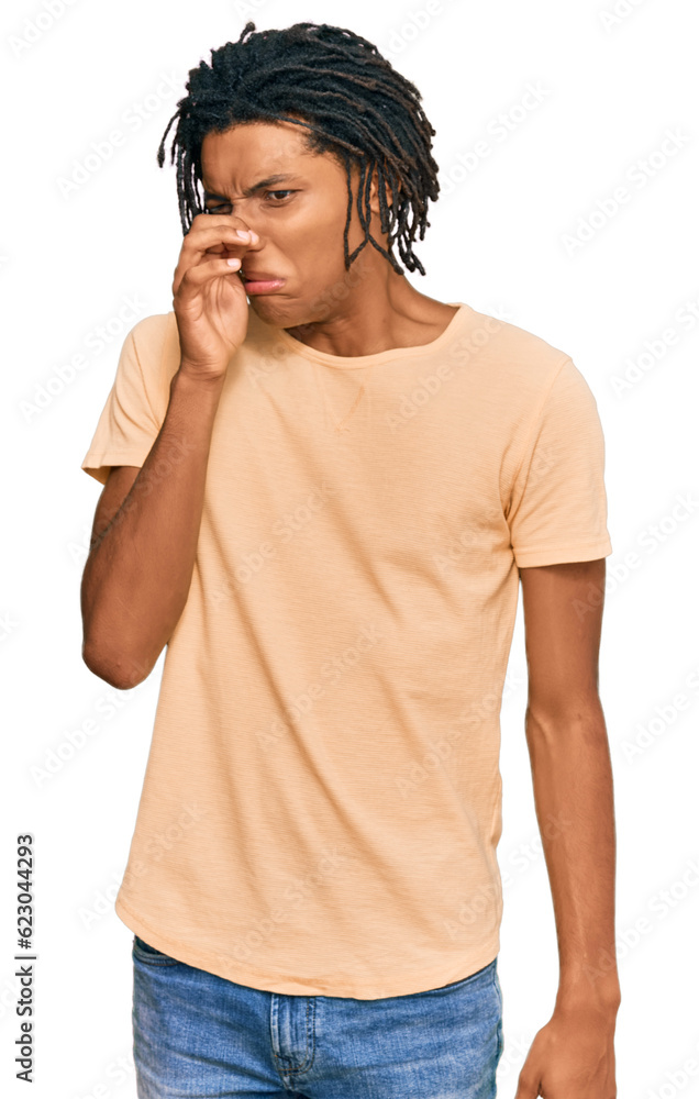 Young african american man wearing casual clothes smelling something stinky and disgusting, intolerable smell, holding breath with fingers on nose. bad smell Young african american man wearing casual clothes smelling something stinky and disgusting, intolerable smell, holding breath with fingers on nose. bad smell