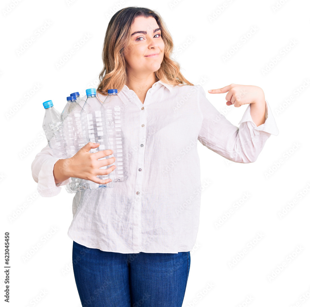 Young caucasian woman holding recycling plastic bottles pointing finger to one self smiling happy and proud Young caucasian woman holding recycling plastic bottles pointing finger to one self smiling happy and proud