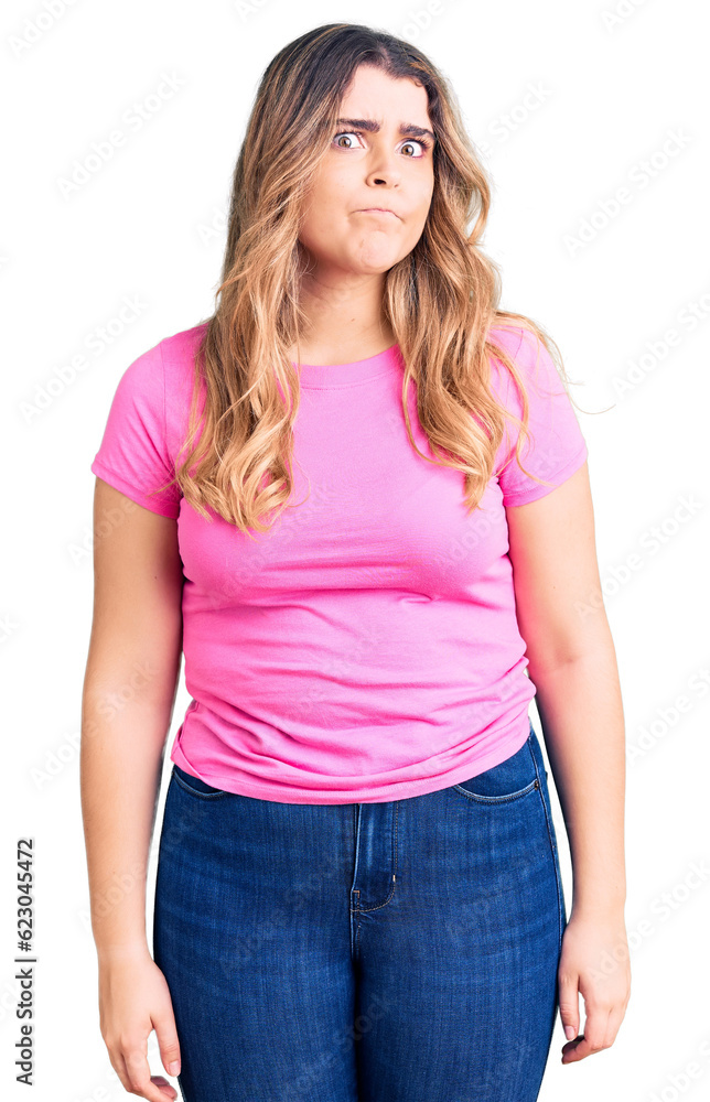 Fototapeta premium Young caucasian woman wearing sportswear puffing cheeks with funny face. mouth inflated with air, crazy expression.