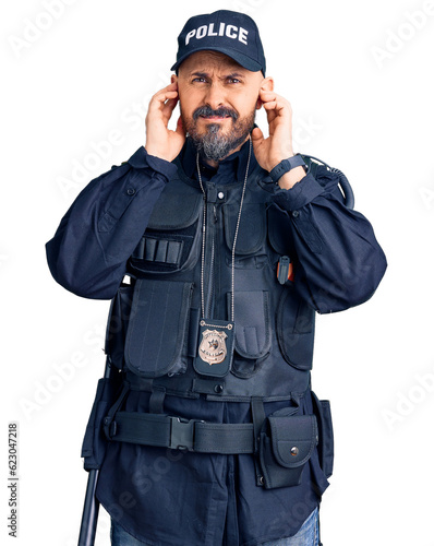Young handsome man wearing police uniform covering ears with fingers with annoyed expression for the noise of loud music. deaf concept.