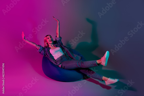 Photo of positive cheerful lady rest relax imagine ride on armchair isolated on fluorescent neon color background