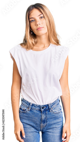 Beautiful caucasian woman with blonde hair wearing casual white tshirt relaxed with serious expression on face. simple and natural looking at the camera.