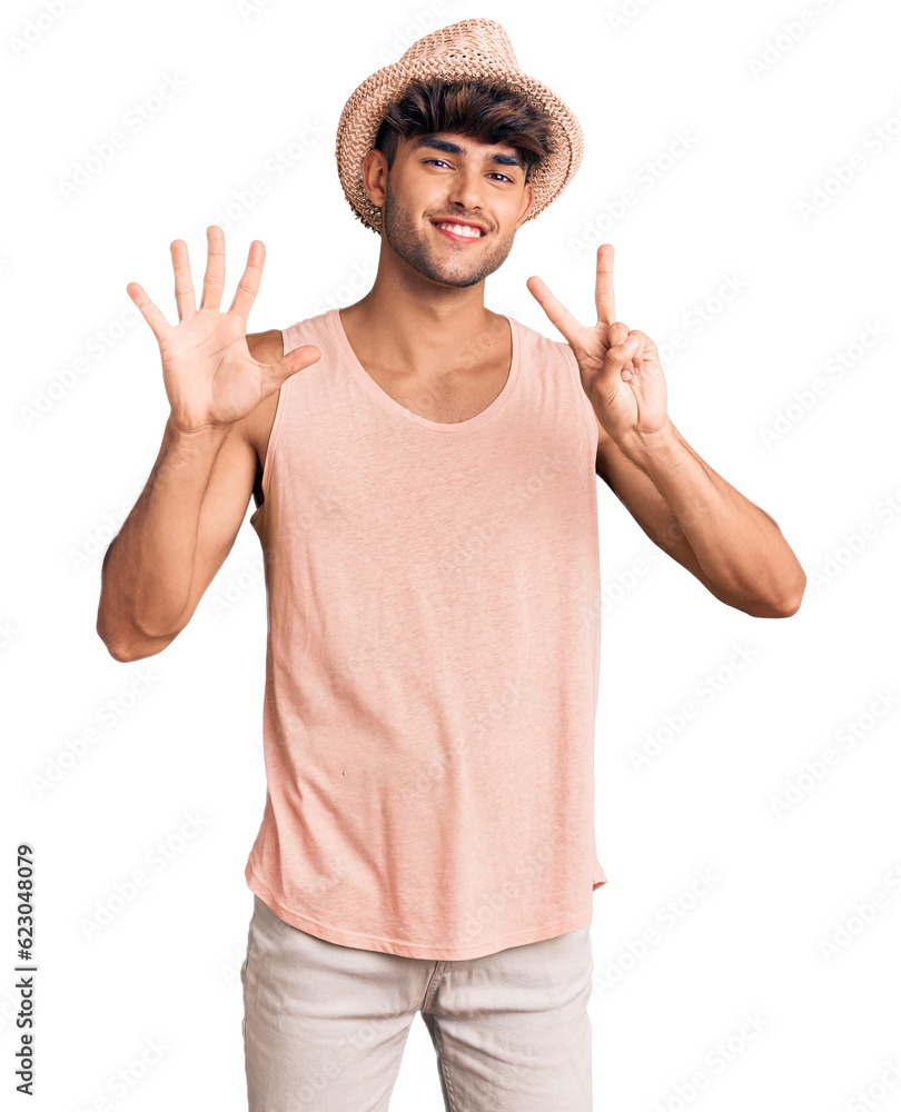 Young hispanic man wearing summer hat showing and pointing up with fingers number seven while smiling confident and happy. Young hispanic man wearing summer hat showing and pointing up with fingers number seven while smiling confident and happy.