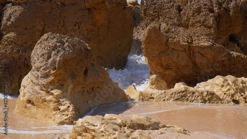 Waves At The Red Rock Cliffs Of Praia do Evaristo Beach In Algarve Portugal. Close Up photo