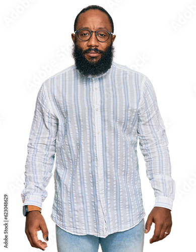 Young african american man wearing business shirt and glasses with serious expression on face. simple and natural looking at the camera.