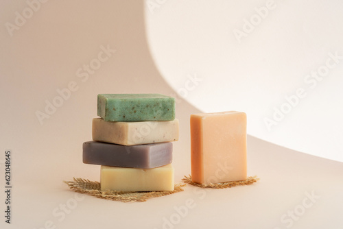 Pattern natural handmade soap of different sizes and colors. Brown background shadows of flowers from the sun. Cosmetic pedestal for product promotion.