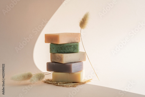 Pattern natural handmade soap of different sizes and colors. Brown background shadows of flowers from the sun. Cosmetic pedestal for product promotion. photo