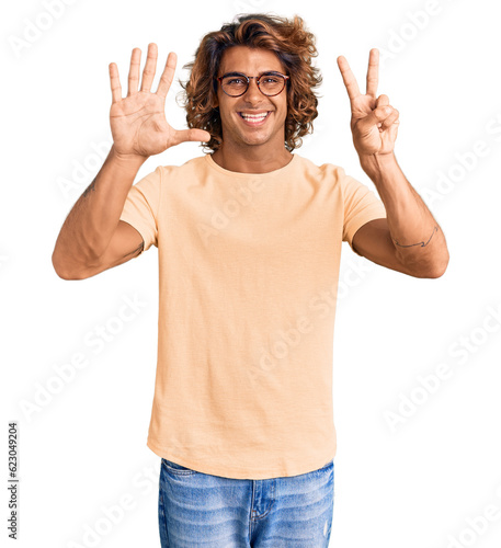 Young hispanic man wearing casual clothes and glasses showing and pointing up with fingers number seven while smiling confident and happy.