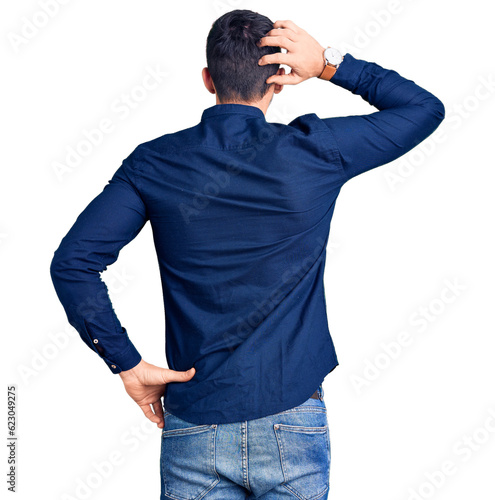 Young handsome man wearing casual shirt backwards thinking about doubt with hand on head