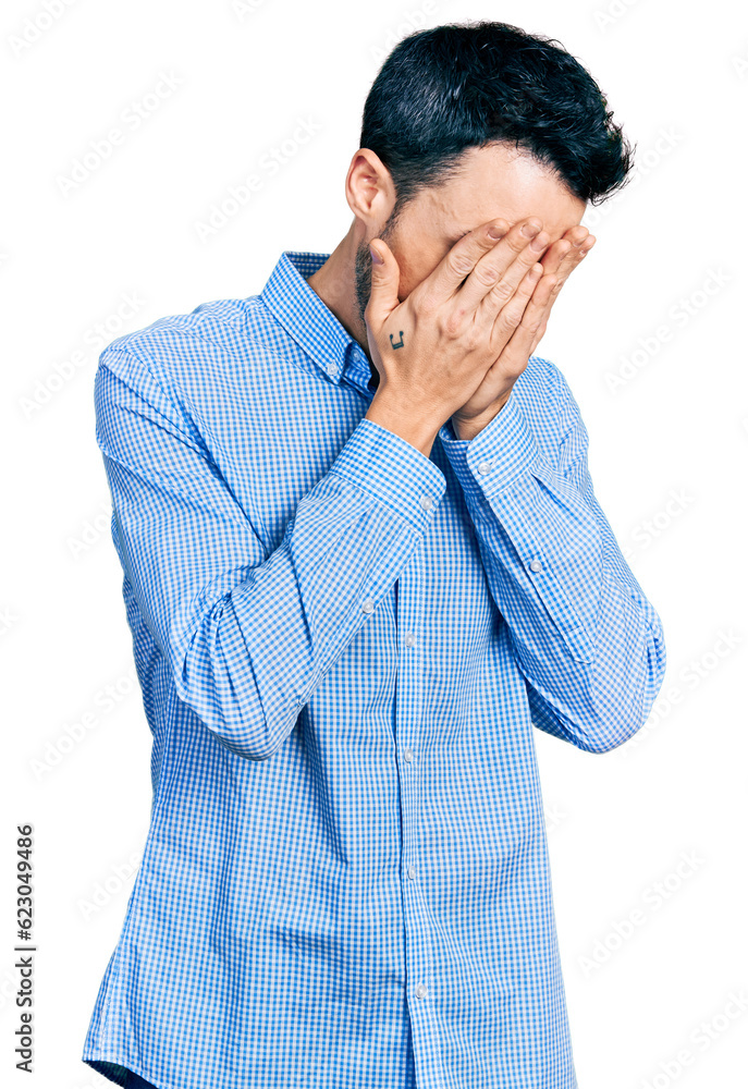 Hispanic man with beard wearing casual business shirt with sad expression covering face with hands while crying. depression concept. Hispanic man with beard wearing casual business shirt with sad expression covering face with hands while crying. depression concept.