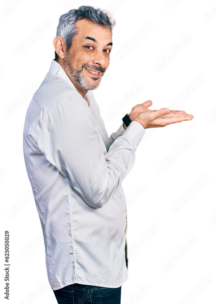 Middle age hispanic with grey hair wearing casual white shirt pointing aside with hands open palms showing copy space, presenting advertisement smiling excited happy Middle age hispanic with grey hair wearing casual white shirt pointing aside with hands open palms showing copy space, presenting advertisement smiling excited happy