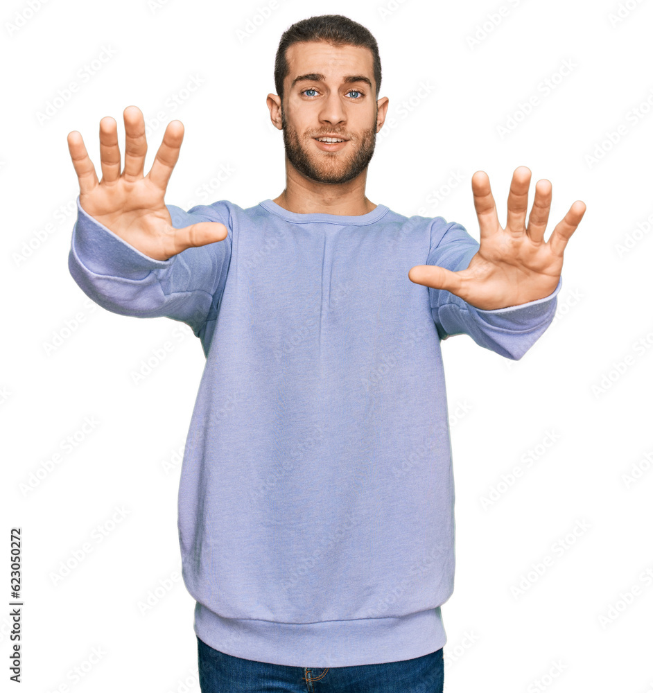 Naklejka premium Young caucasian man wearing casual clothes afraid and terrified with fear expression stop gesture with hands, shouting in shock. panic concept.