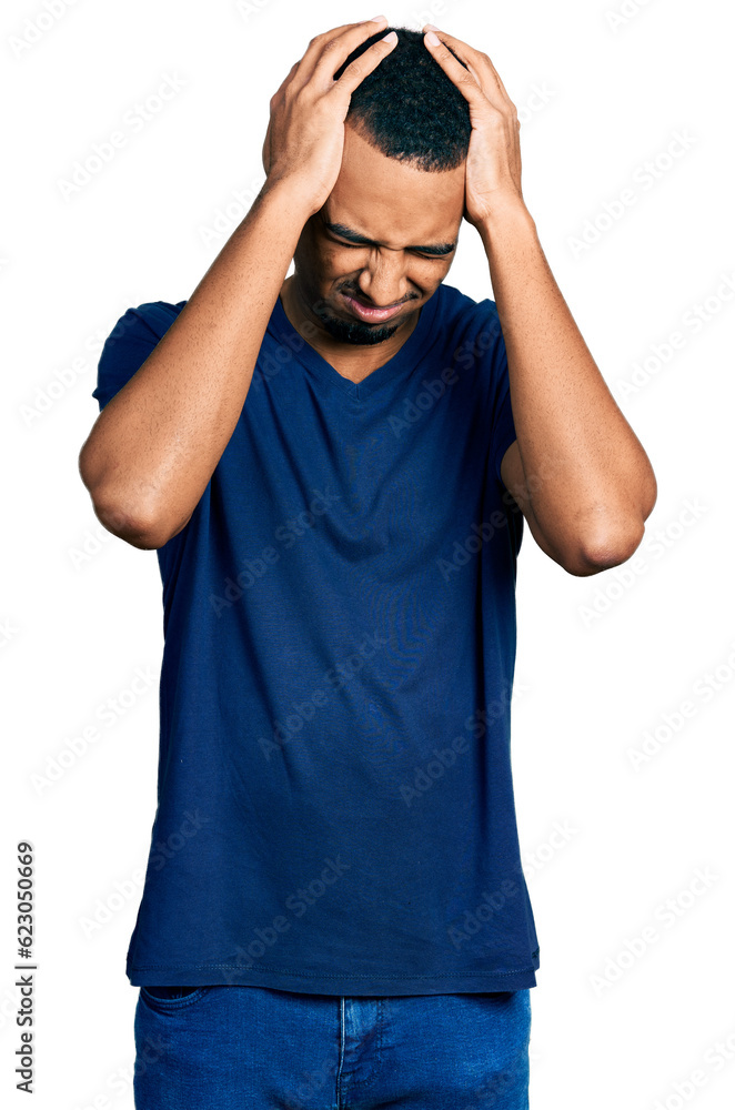 Young african american man wearing casual t shirt suffering from headache desperate and stressed because pain and migraine. hands on head. Young african american man wearing casual t shirt suffering from headache desperate and stressed because pain and migraine. hands on head.