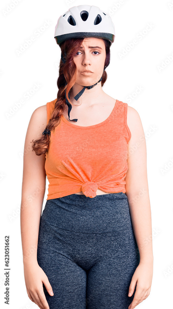 Young beautiful woman wearing bike helmet with serious expression on face. simple and natural looking at the camera. Young beautiful woman wearing bike helmet with serious expression on face. simple and natural looking at the camera.