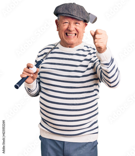 Senior handsome grey-haired man holding golf club and ball annoyed and frustrated shouting with anger, yelling crazy with anger and hand raised