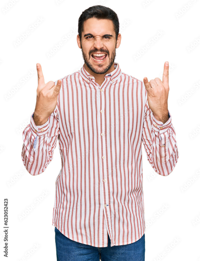 Young hispanic man wearing business shirt shouting with crazy expression doing rock symbol with hands up. music star. heavy concept. Young hispanic man wearing business shirt shouting with crazy expression doing rock symbol with hands up. music star. heavy concept.