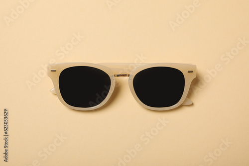 Beige sunglasses on a beige background, top view