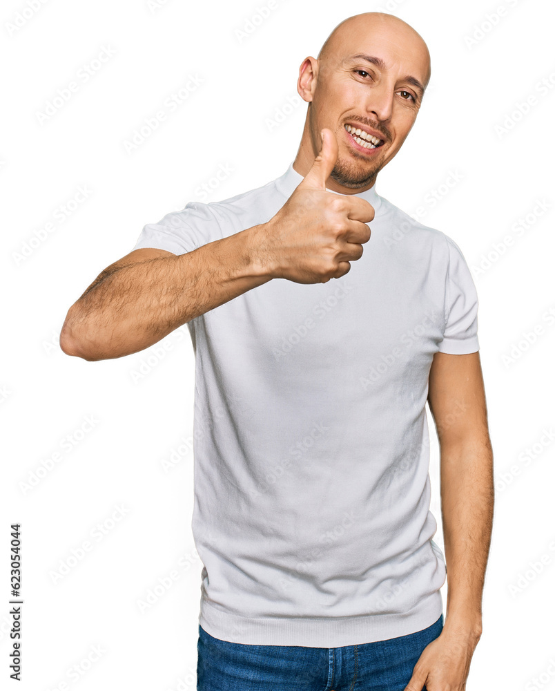 Bald man with beard wearing casual white t shirt doing happy thumbs up gesture with hand. approving expression looking at the camera showing success. Bald man with beard wearing casual white t shirt doing happy thumbs up gesture with hand. approving expression looking at the camera showing success.