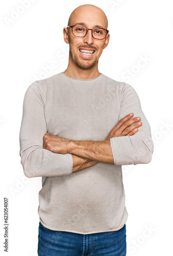 Bald man with beard wearing casual clothes and glasses happy face smiling with crossed arms looking at the camera. positive person.