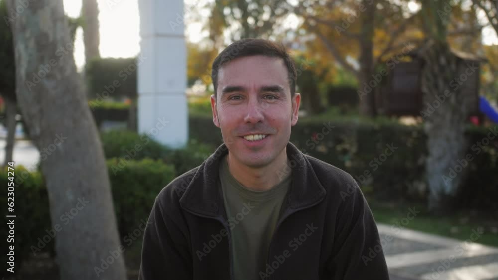 Close-up portrait of young handsome Arab standing outdoors alone smiling looking at camera.