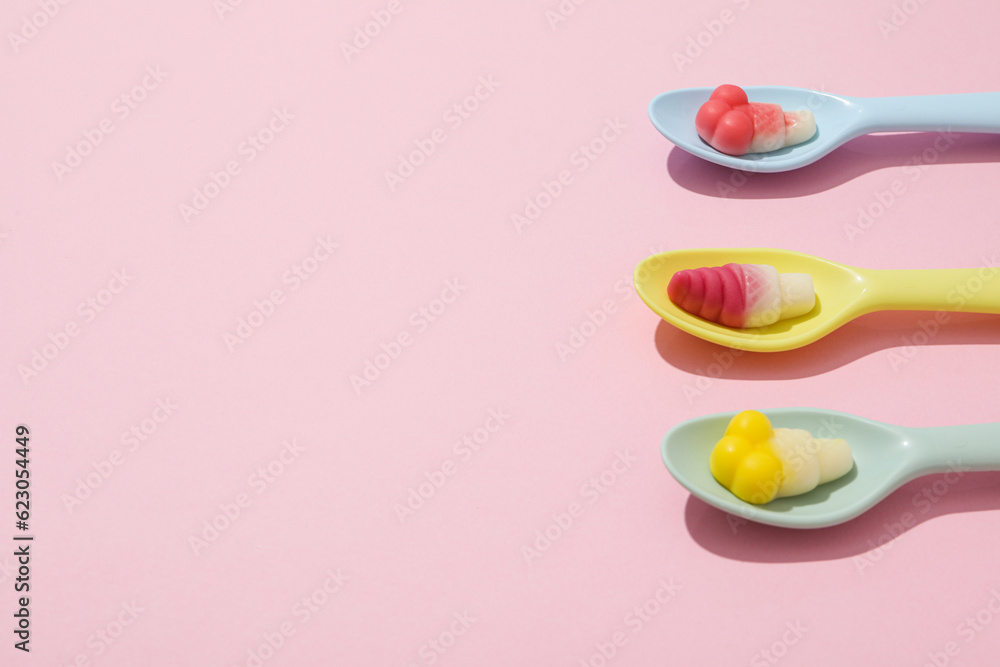 Jelly candies in spoons on pink background, space for text Jelly candies in spoons on pink background, space for text