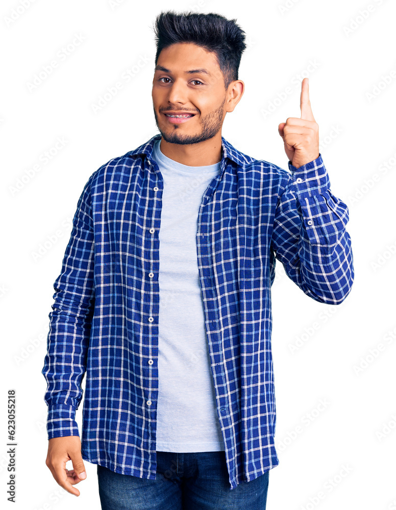 Handsome latin american young man wearing casual shirt pointing finger up with successful idea. exited and happy. number one. Handsome latin american young man wearing casual shirt pointing finger up with successful idea. exited and happy. number one.