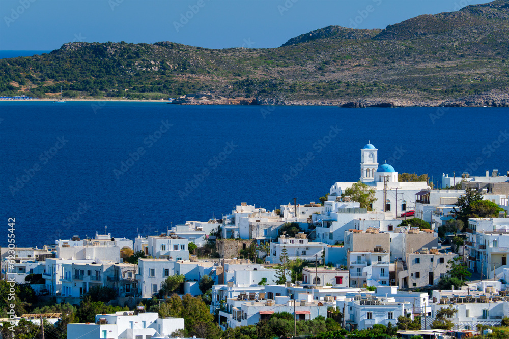 View of Plaka village with traditional Greek orthodox church and white painted houses and ocean coast. Milos island, Greece