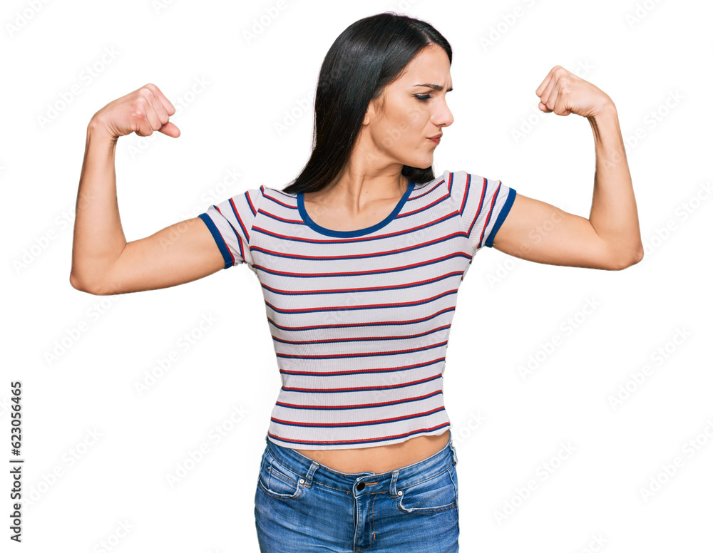 Young hispanic girl wearing casual striped t shirt showing arms muscles smiling proud. fitness concept. Young hispanic girl wearing casual striped t shirt showing arms muscles smiling proud. fitness concept.