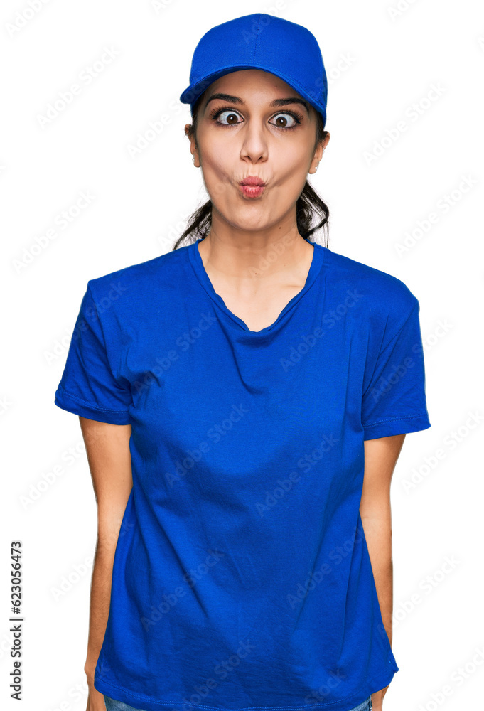 Young hispanic girl wearing delivery courier uniform making fish face with lips, crazy and comical gesture. funny expression.