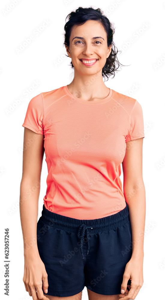 Obraz premium Young beautiful hispanic woman wearing sportswear looking positive and happy standing and smiling with a confident smile showing teeth