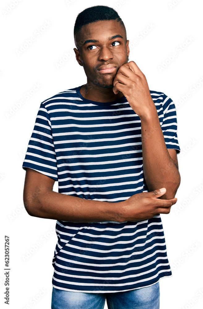 Young african american man wearing casual striped t shirt thinking concentrated about doubt with finger on chin and looking up wondering Young african american man wearing casual striped t shirt thinking concentrated about doubt with finger on chin and looking up wondering