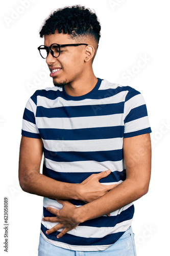 Young african american man wearing casual clothes and glasses with hand on stomach because nausea, painful disease feeling unwell. ache concept.