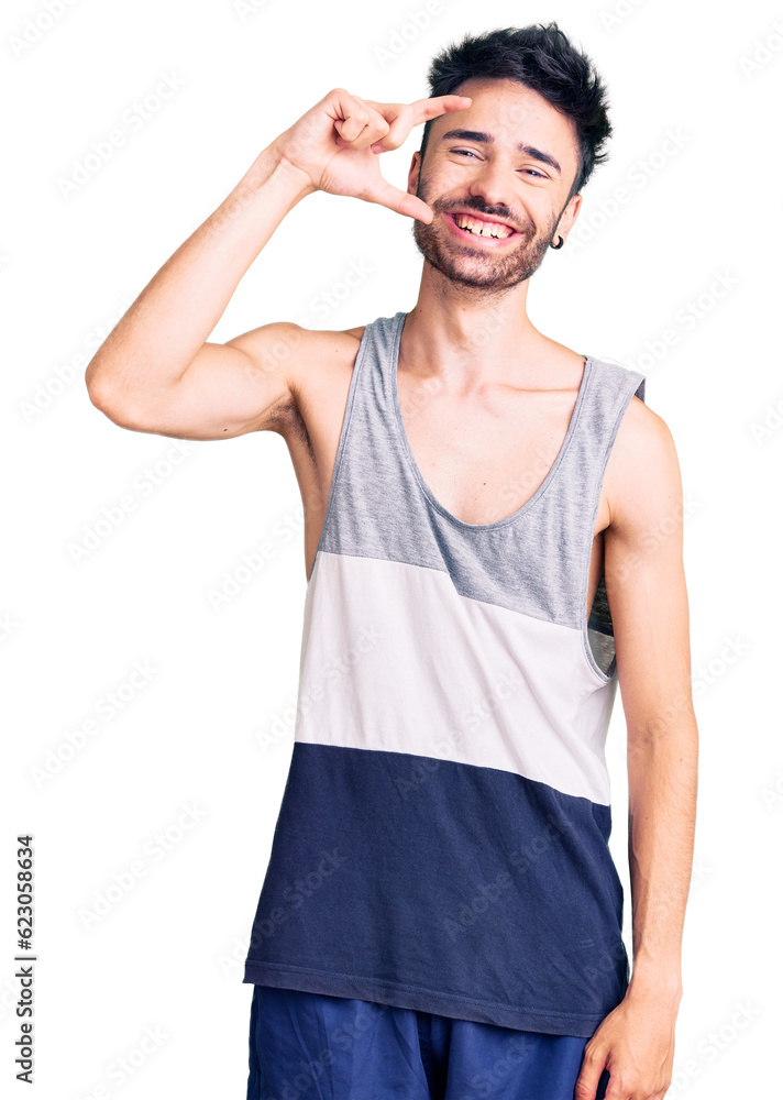 Young hispanic man wearing casual clothes smiling and confident gesturing with hand doing small size sign with fingers looking and the camera. measure concept. Young hispanic man wearing casual clothes smiling and confident gesturing with hand doing small size sign with fingers looking and the camera. measure concept.