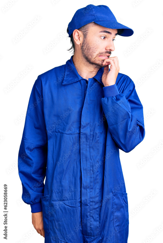 Young hispanic man wearing painter uniform looking stressed and nervous with hands on mouth biting nails. anxiety problem.