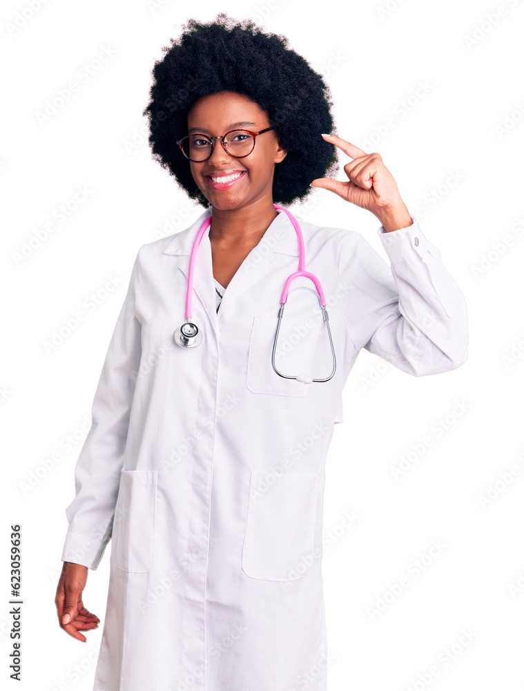 Young african american woman wearing doctor coat and stethoscope smiling and confident gesturing with hand doing small size sign with fingers looking and the camera. measure concept.
