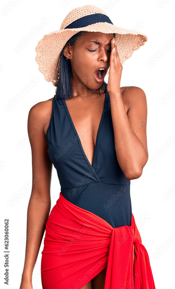 Young african american woman wearing swimsuit and summer hat yawning tired covering half face, eye and mouth with hand. face hurts in pain. Young african american woman wearing swimsuit and summer hat yawning tired covering half face, eye and mouth with hand. face hurts in pain.