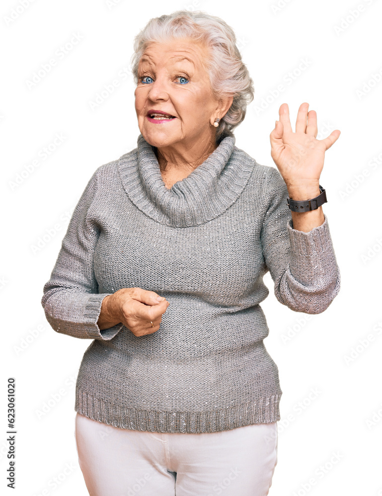 Senior grey-haired woman wearing casual winter sweater waiving saying hello happy and smiling, friendly welcome gesture Senior grey-haired woman wearing casual winter sweater waiving saying hello happy and smiling, friendly welcome gesture