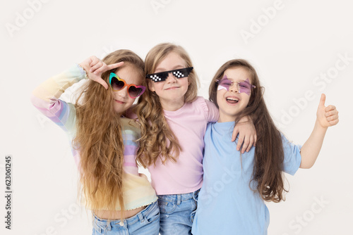 Group portrait of kids girls friends on white studio background. Happy children  cute girls hugging and having fun in carnival glasses. funny faces