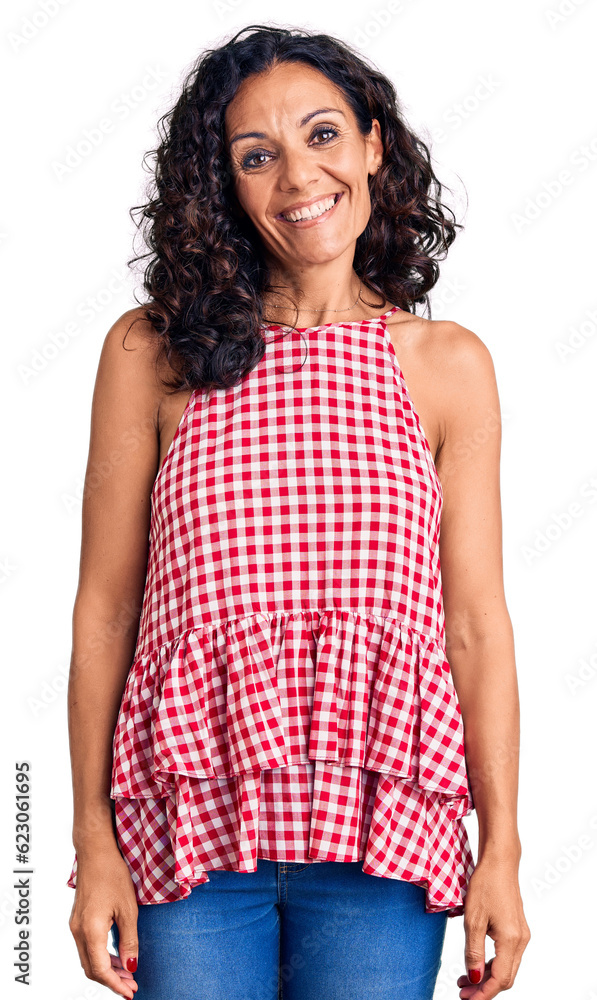 Middle age beautiful woman wearing casual sleeveless t shirt looking positive and happy standing and smiling with a confident smile showing teeth Middle age beautiful woman wearing casual sleeveless t shirt looking positive and happy standing and smiling with a confident smile showing teeth