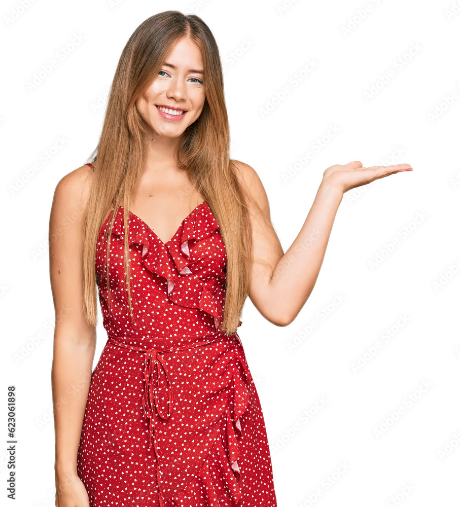 Beautiful blonde woman wearing summer dress smiling cheerful presenting and pointing with palm of hand looking at the camera. Beautiful blonde woman wearing summer dress smiling cheerful presenting and pointing with palm of hand looking at the camera.