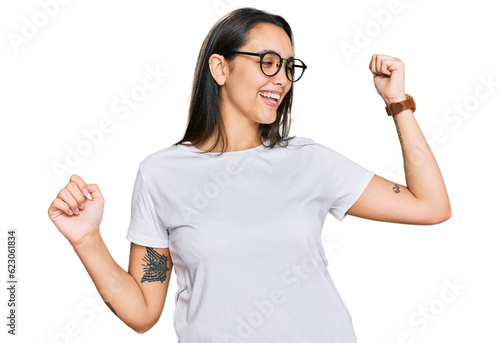 Young hispanic woman wearing casual white t shirt dancing happy and cheerful, smiling moving casual and confident listening to music