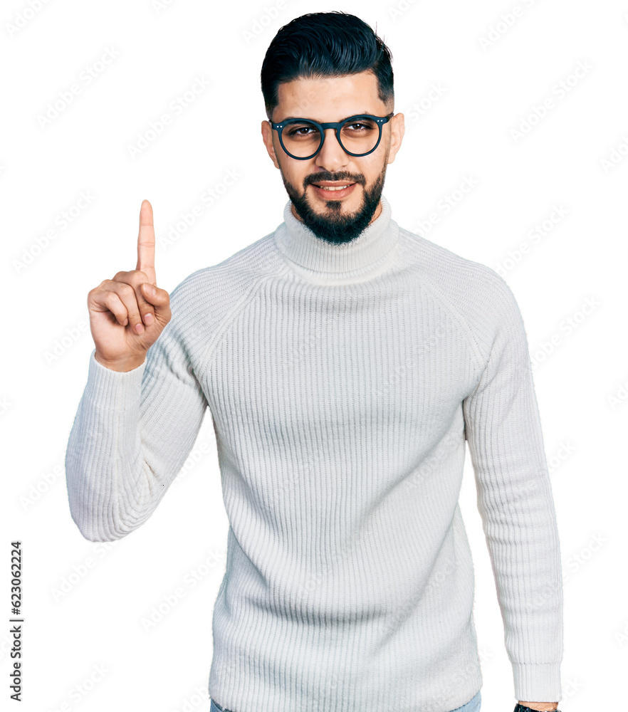 Young arab man with beard wearing elegant turtleneck sweater and glasses showing and pointing up with finger number one while smiling confident and happy. Young arab man with beard wearing elegant turtleneck sweater and glasses showing and pointing up with finger number one while smiling confident and happy.