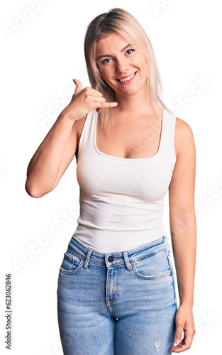 Young beautiful blonde woman wearing casual sleeveless t-shirt smiling doing phone gesture with hand and fingers like talking on the telephone. communicating concepts.